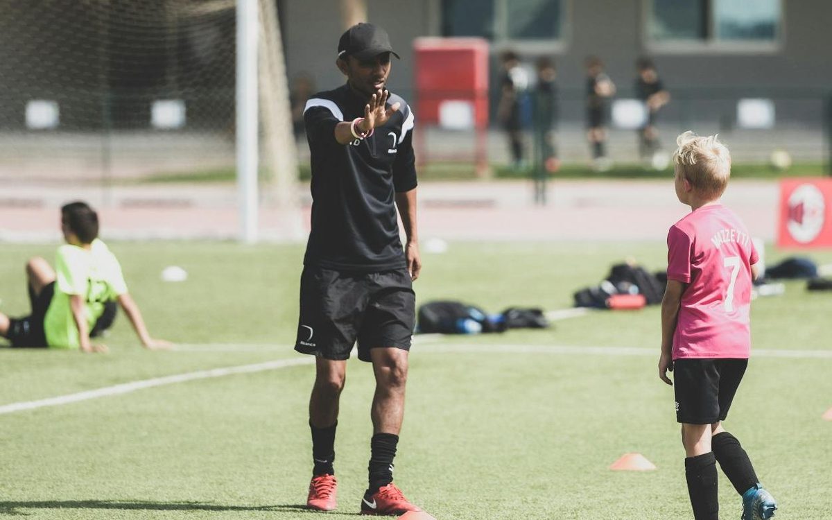 Un éducateur guide un jeune joueur à l'entraînement